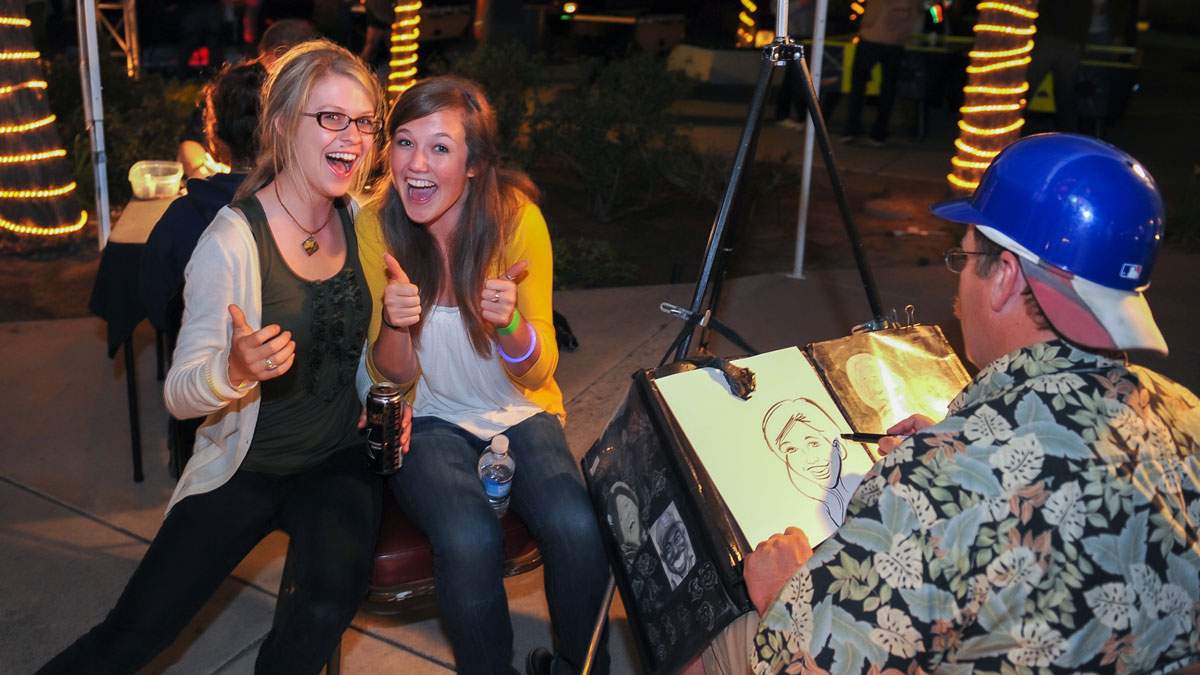 Two students have their caricuture drawn while they enjoy a Grad Night produced by James Event Productions.